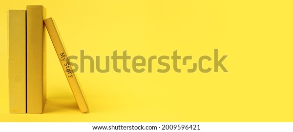 Yellow books on vibrant\
yellow background banner. One book with words my story written on\
book spine.