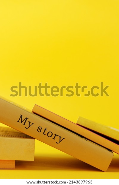 Yellow books on vibrant yellow\
background. One book with words my story written on book\
spine.