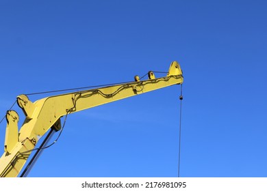 The Yellow Boom Crane Is Being Lifted Up While The Lube Oil Drum Is Lifting Against A Bright Blue Sky Background