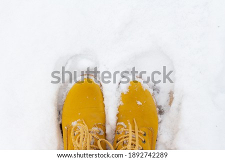Yellow boots stand in white snow