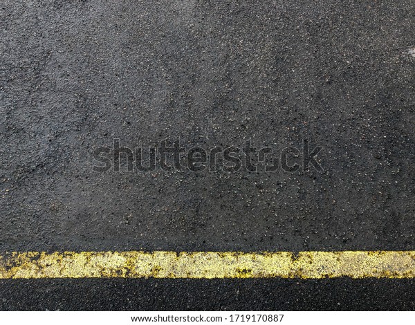 A yellow boundary line on the wet asphalt.\
Texture, wallpaper