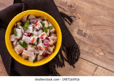 A Yellow Bowl With Ceviche On A Wooden Table