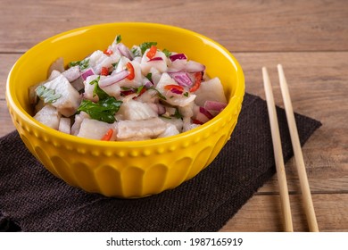 A Yellow Bowl With Ceviche On A Wooden Table