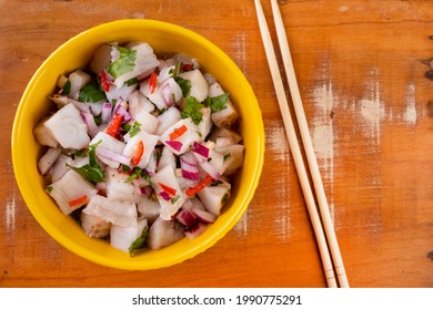 A Yellow Bowl With Ceviche On A Wooden Table.