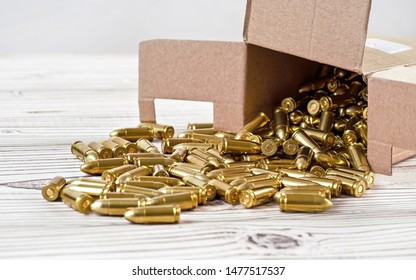 Yellow Brass Gun Ammo Spilled From Paper Carton Box On White Boar Desk - Close Up