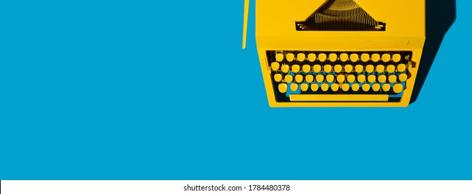 Yellow Bright Typewriter On Blue. Symbol For Writing, Blogging, New Ideas And Creativity. Copy Space Banner