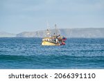 Yellow British fishing boat trawler alone in the English channel islands waters after leaving EU with no French fisherman boats or nets in view. Territorial waters under England