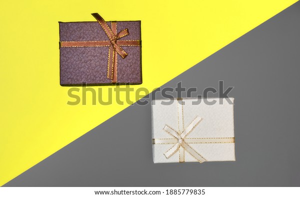 Yellow and brown gift\
packages on a modern yellow and gray background, divided by a\
diagonal line.