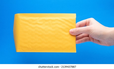 Yellow Bubble Mailer In Hand On A Blue Background