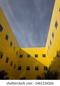 Yellow buildings with sharp shadow and small clouds on a summer day