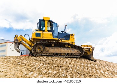 Yellow bulldozer on tracks at the mountain road construction