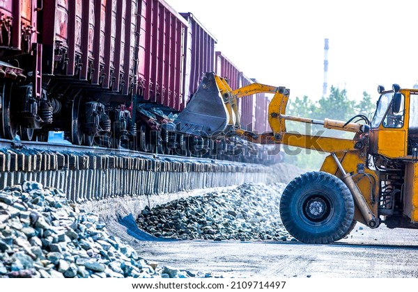 Yellow bulldozer\
working in quarry near\
train
