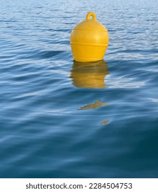 A yellow buoy in blue water with small waves