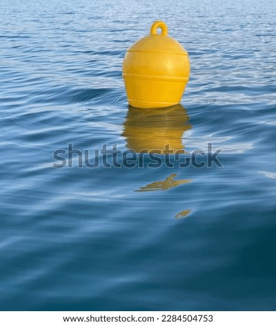 A yellow buoy in blue water with small waves