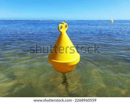 Yellow buoy floating in turquoise water of the caribbean sea under tropical blue sky. Navigation, signaling and maritime safety in the French Antilles.