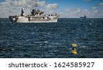 A yellow buoy sits in Tokyo Bay just off the coast of Yokosuka, Japan with a US Navy ship heading out to sea.
