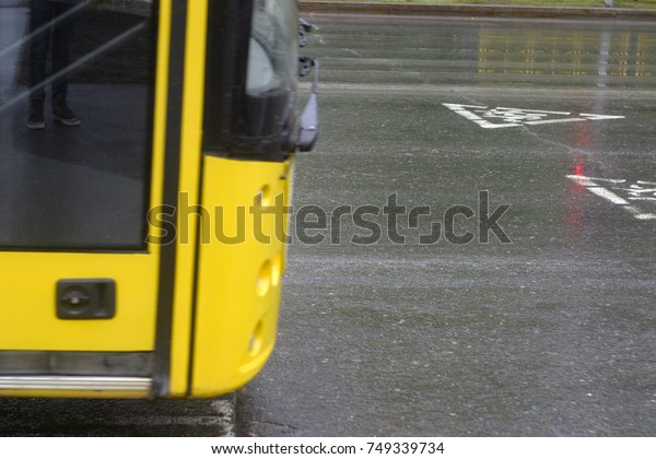 Yellow bus rides on an asphalt road wet from\
rain. Summer and autumn\
background