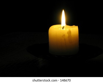 A Yellow Candle Lit In A Very Dark Room,You Can Only See The Top Part Of The Candle And The Flame,