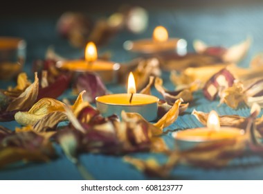 yellow candles and plamennoi surrounded by dry petals of tulips on blue wooden boards