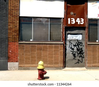 Yellow capped fire hydrant in front of an abandoned building