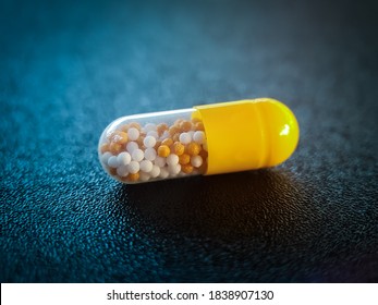 Yellow Capsule On A Black Table With Blue Background. Medication For Treatment Covid 19 Infection, High Blood Pressure, Malaria, Antibiotics, Diabetes