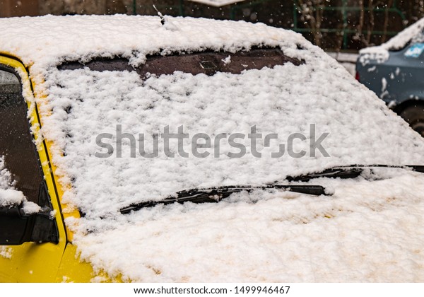 Yellow Car covered with snow in the winter\
blizzard.Extreme\
snowfall