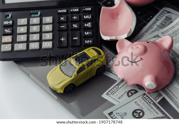 Yellow car and dollars bills with broken piggy\
bank. Insurance concept