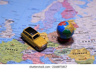 Yellow Car On The Map Of Europe. From Above Car On Europe Map. The Composition Of The Yellow Car Model Stands On.