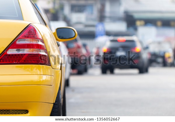 Yellow car parked in line parking lot with car\
running background