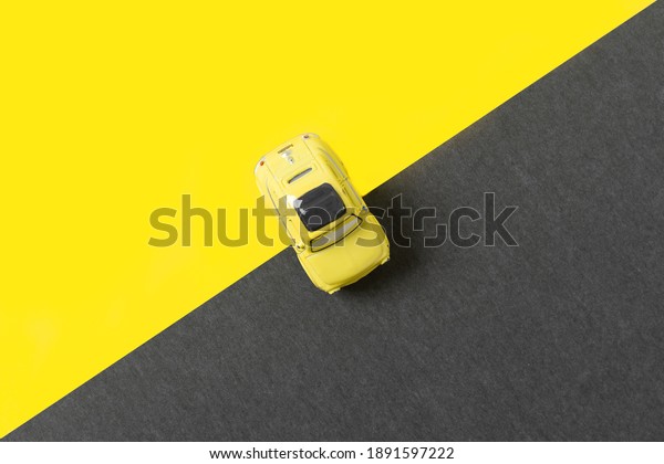 Yellow car toy on trendy yellow gray background\
with copy space. Illuminating Yellow and Ultimate Gray, new colors\
of the year 2021.