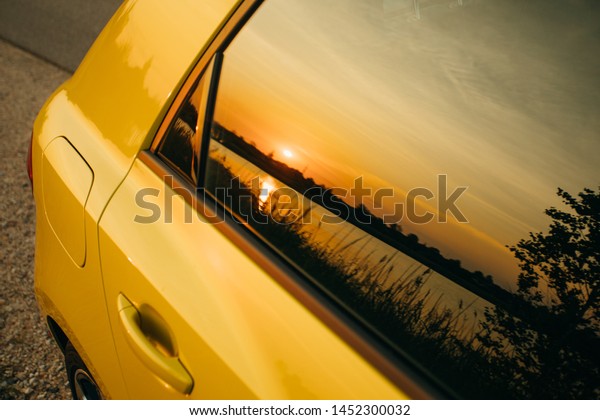 Yellow car window with\
Sunset Reflection