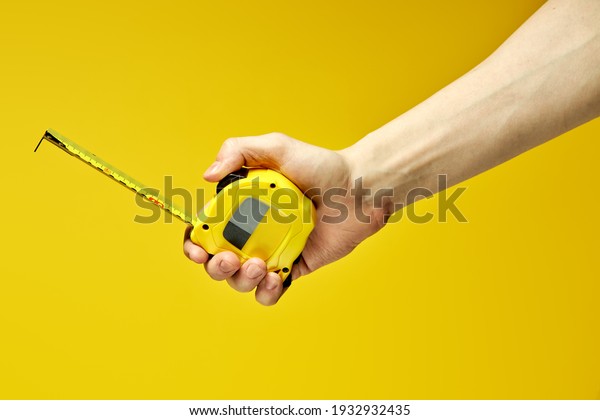 Yellow carpenter measuring\
tape with an imperial units scale isolated on yellow background,\
copy space
