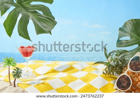 The yellow carpet with checkered pattern spread on sand beach side with a watermelon juice glass, pineapple and monstera leaves decorated above, over the sea and sky background. Vacant space in center