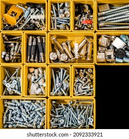 Yellow case with small construction objects. Many storage compartments filled with builders accessories containing screws, nuts, bolts, nails and other tools in workshop. Arranged neatly and organized