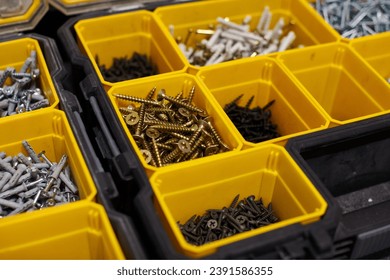 Yellow case with small construction objects. Many storage compartments filled with builders accessories containing screws, nuts, bolts, nails and other tools in workshop. Arranged neatly and organized - Powered by Shutterstock