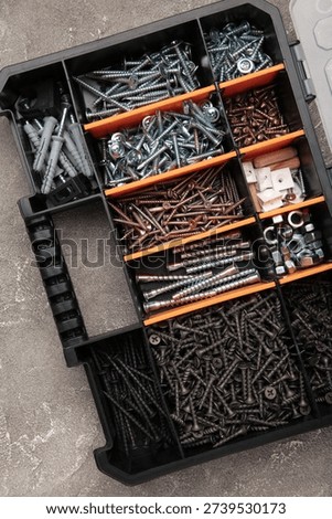 Yellow case with small construction objects on grey background. Vertical photo