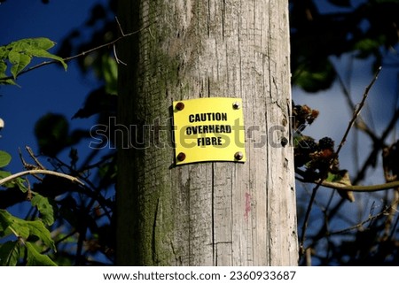 Yellow caution overhead fibre sign on a timber pole