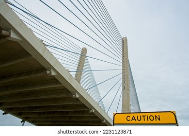 Yellow caution sign under cable-stayed bridge viewed from below. The Charles W. Cullen Memorial Bridge, a Harp design with stays running nearly parallel between tower and deck attachments.