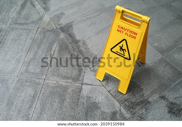 Yellow\
Caution slippery wet floor sign on the wet\
ground
