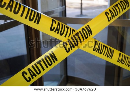 Yellow CAUTION tape barring exit through a door