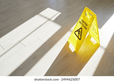 Yellow caution wet floor sign stands on the floor during maintenance, warning of slippery conditions. This safety sign helps prevent slips and falls during cleaning and purification activities. - Powered by Shutterstock