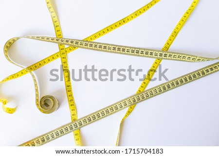 Yellow centimetre tape crossed on white background