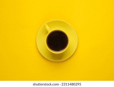 Yellow ceramic cup with coffee on a saucer, yellow background. Top view - Powered by Shutterstock