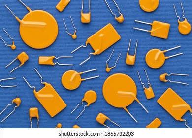 Yellow ceramic and polyester film capacitors of a square and round shape on a blue background close-up. Top view