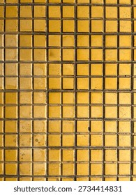 Yellow ceramic tile texture with small square patterns, creating a warm geometric background for design and architecture.