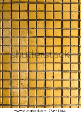 Yellow ceramic tile texture with small square patterns, creating a warm geometric background for design and architecture.