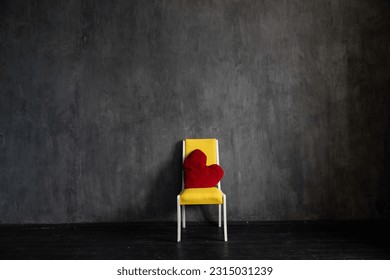 yellow chair pillow in the shape of a heart on a gray background interior in a dark room - Powered by Shutterstock