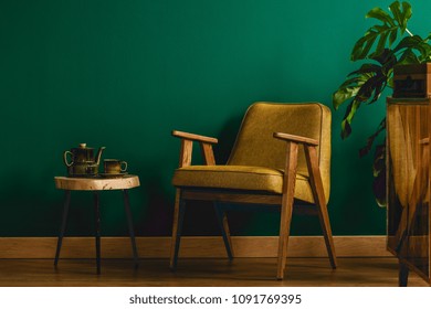 Yellow Chair In A Vintage Room Interior With Green Wall, Stool, Cabinet, Teapot And Plant