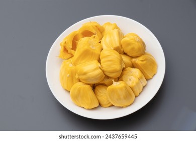 Yellow Champedak sliced in white plate and gray background. Ripe jackfruit in white plate.