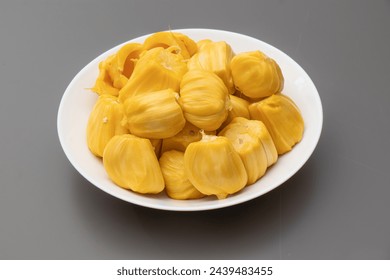Yellow Champedak sliced in white plate and gray background. Ripe jackfruit in white plate.